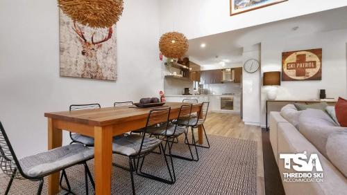 a dining room and living room with a table and chairs at Snowbound Chalet 5 in Thredbo