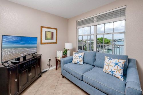 a living room with a blue couch and a flat screen tv at 406 Dockside in Clearwater Beach