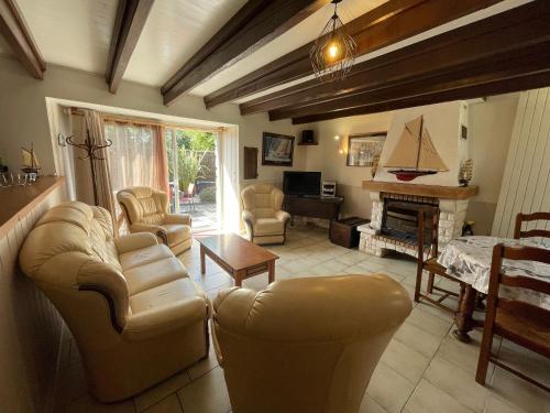 Elle comprend un salon doté d'un mobilier en cuir et d'une cheminée. dans l'établissement Gîte Charmant avec Cheminée, Jardin Clos et Equipements Bébé à Proximité de la Côte - FR-1-306-842, à Saint-Molf