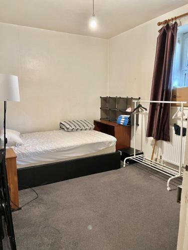 a bedroom with a bed and a desk and a window at Live in White City in London
