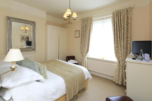 a bedroom with a bed and a mirror and a window at The Old Vicarage Dolfor in Newtown