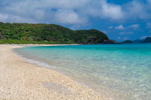 a beach with a mountain in the background at Kerama Blue Resort in Zamami