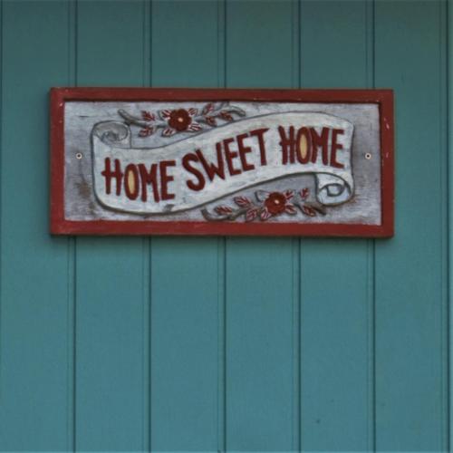 a home sweet home sign on a blue wall at Bay of Islands Lodge in Paihia
