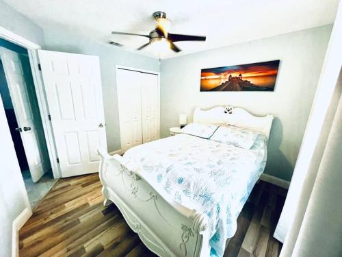 a bedroom with a white bed and a ceiling fan at Heated Pool home fenced yard near the beach in Palm Coast