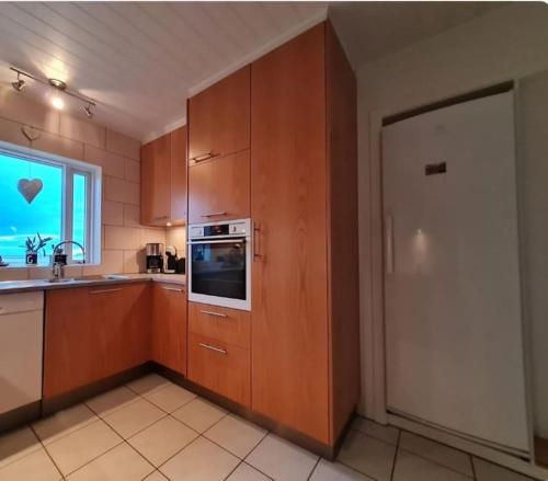 a kitchen with wooden cabinets and a sink and a microwave at Ibúð með einstöku útsýni in Sauðárkrókur