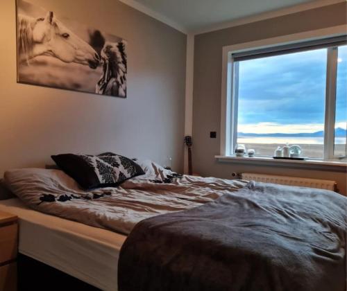 um quarto com uma cama grande e uma janela em Ibúð með einstöku útsýni em Sauðárkrókur