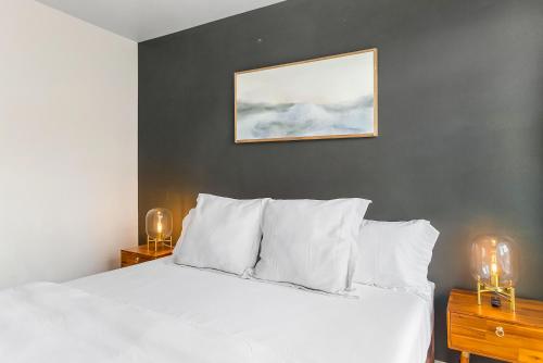 a bedroom with a white bed with a picture on the wall at Belltown Perch, explore like a local 99 Walkscore in Seattle