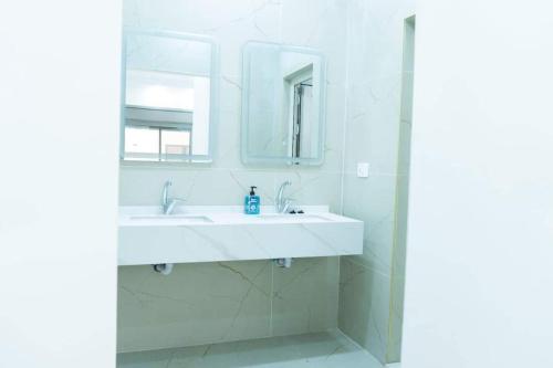 Baño blanco con lavabo y espejo en شاليه سد الموجب, en Al Mara‘ah