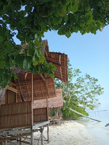 a resort on the beach with a tree at Nyande Rengkri Guest House in Kri