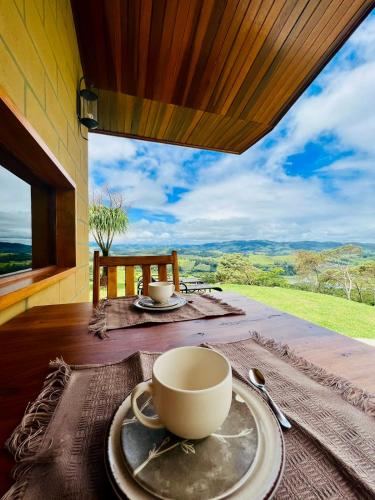 a table with a cup and a plate on a table at Chalé com borda infinita vista para represa in Joanópolis
