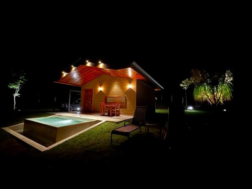 a small house with a swimming pool at night at Chalé com borda infinita vista para represa in Joanópolis
