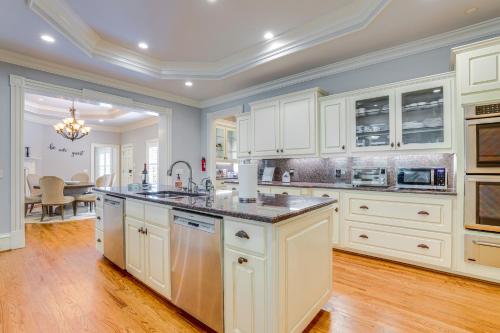 a large kitchen with white cabinets and a table at Buford Mansion with Pool about 14 Mi to Lake Lanier in Buford