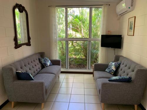 a living room with two couches and a television at Shambhala Retreat Magnetic Island Cottages in Nelly Bay