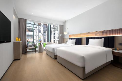 Cette chambre comprend deux lits et une télévision. dans l'établissement voco Lianyungang Haizhou Bay, an IHG Hotel, à Lianyungang