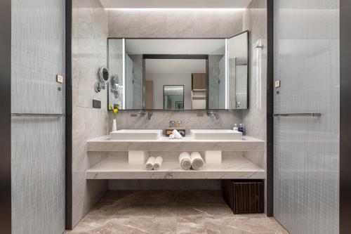 La salle de bains est pourvue de 2 lavabos et d'un grand miroir. dans l'établissement voco Lianyungang Haizhou Bay, an IHG Hotel, à Lianyungang