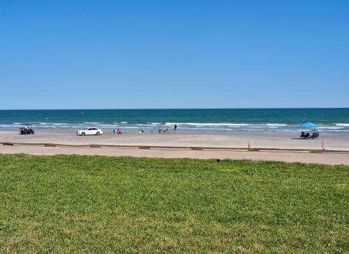 a beach with a car driving down a road at On the Beach Beachfront Condo Direct View & Access to Beach Heated Pool Island House Condominiums Unit 113 in Padre Island