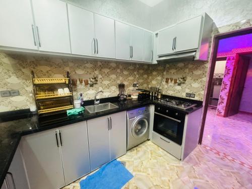 a kitchen with white cabinets and a sink and a dishwasher at Villa Salah in Marrakech