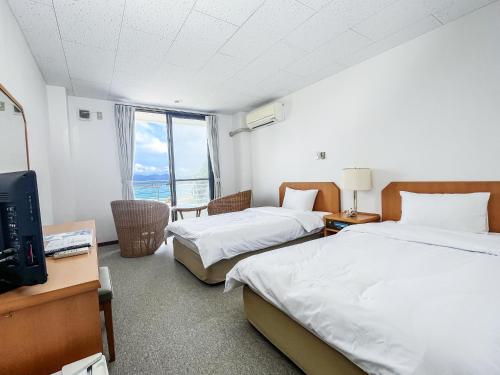 una camera d'albergo con due letti e una televisione di ケラマブルーリゾート a Zamami