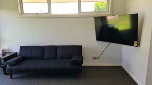 a living room with a couch and a flat screen tv at Tonny Cottage in Tongala