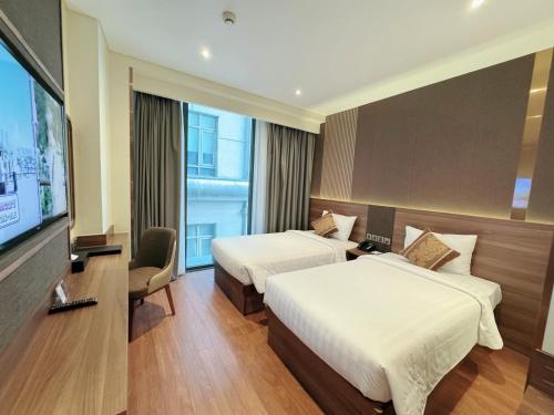 a hotel room with two beds and a flat screen tv at Northern Charm Hotel in Ho Chi Minh City