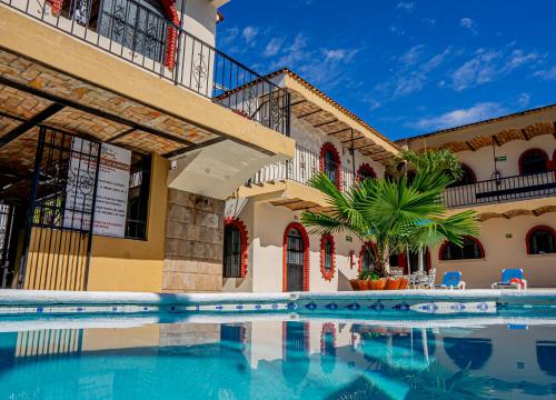 a swimming pool in front of a building at Bungalows Maria Teresa in Rincon de Guayabitos