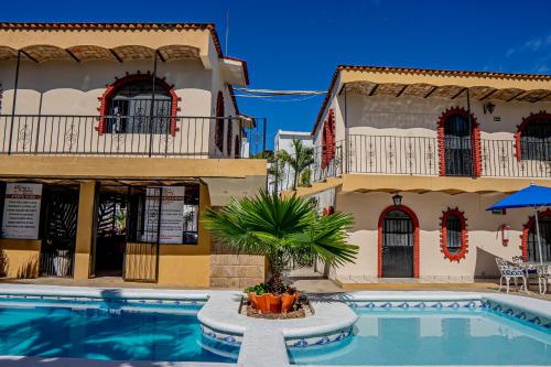 a hotel with a swimming pool in front of two buildings at Bungalows Maria Teresa in Rincon de Guayabitos