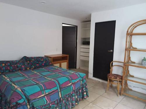 - une chambre avec un lit, une chaise et une étagère dans l'établissement Casa Minimalista Bosques- 3 pisos, à Oaxtepec