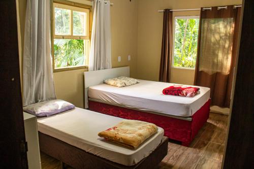 two beds in a room with two windows at Hostel Rio do Boi in Praia Grande