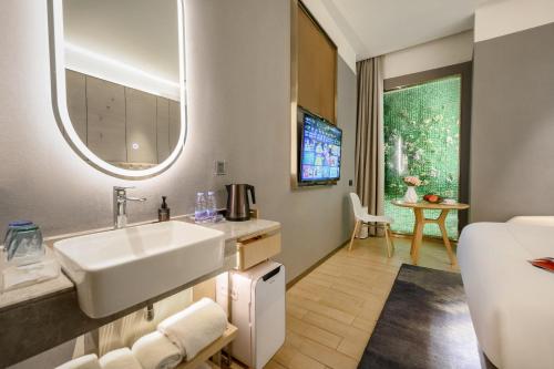 La salle de bains est pourvue d'un lavabo et d'un miroir. dans l'établissement Lux Cabins Hotel Shenzhen, à Shenzhen