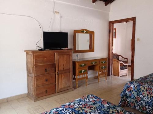 1 dormitorio con TV en un tocador y espejo en Hotel Cabañas Chalamu, en Pátzcuaro