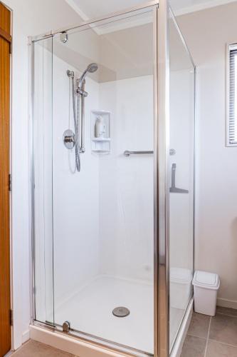 a shower with a glass door in a bathroom at Harbourside Cove, Water Views, Cosy, Peaceful in Raglan