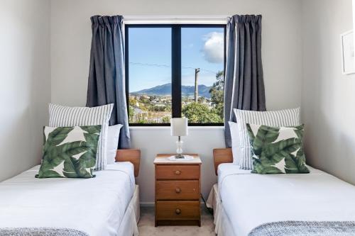 two beds in a room with a window at Harbourside Cove, Water Views, Cosy, Peaceful in Raglan