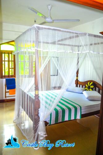 a bedroom with a canopy bed with white drapes at Castle Bay Resort in Weligama