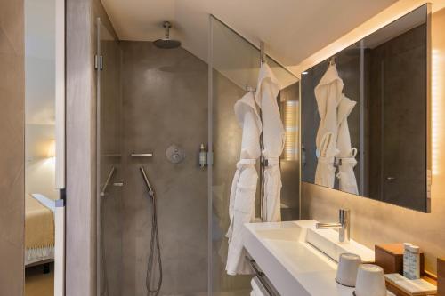 a bathroom with a shower and a sink and a mirror at Memmo Alfama - Design Hotels in Lisbon