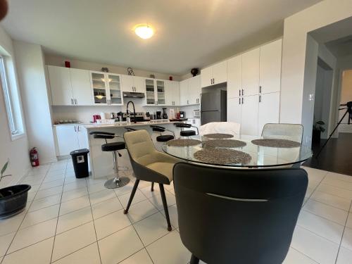 une grande cuisine avec une table et des chaises en verre dans l'établissement Brand new luxurious home, located in Lindsay., à Kawartha Lakes
