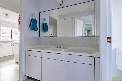 a white bathroom with a sink and a mirror at Waterfront on Plover in Sussex inlet