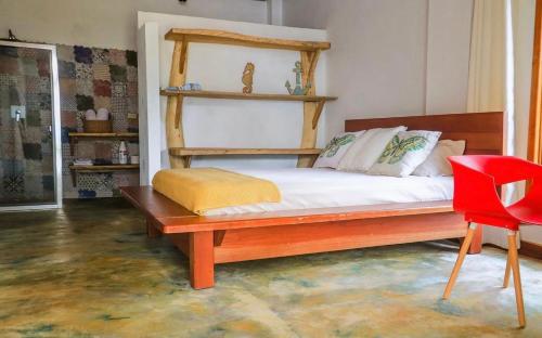 1 dormitorio con cama de madera y silla roja en Kudos club en Las Lajas