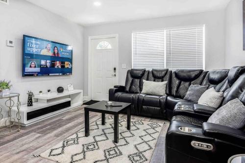 a living room with a black leather couch and a tv at Mazor Luxury Two bedroom vacation Home in Fort Lauderdale
