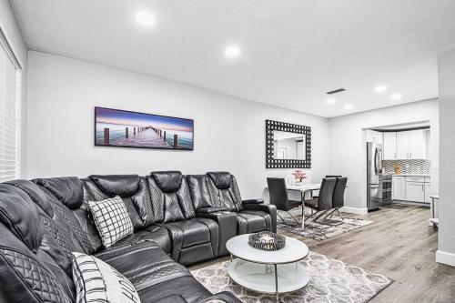 a living room with a black leather couch and a table at Rachaels upscale Two bedrooms Luxury Home in Fort Lauderdale