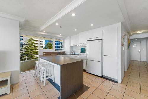 a kitchen with white cabinets and a large island at Zenith Ocean Front Apartments in Gold Coast