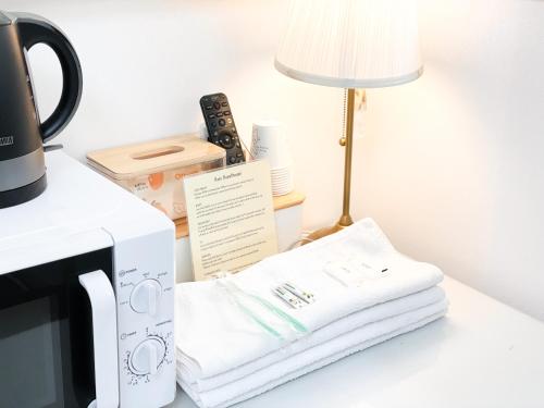 a microwave on a table with a lamp and a stack of towels at Koin Guesthouse Incheon airport in Incheon