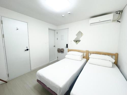 twee bedden in een kamer met witte muren bij Koin Guesthouse Incheon airport in Incheon