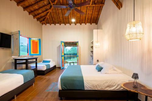 ein Schlafzimmer mit zwei Betten und einem Deckenventilator in der Unterkunft Casa Saman by tesorito fincas exclusivas in Armenia