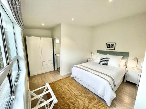 une chambre avec un grand lit blanc et une fenêtre dans l'établissement Sailor's Cottage - Stay Waiheke, à Blackpool