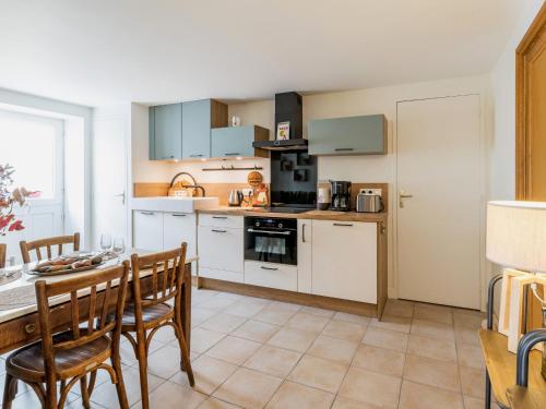a kitchen with white cabinets and a table and chairs at Évasion en Gîte de Charme avec Jardin, Piscine Chauffée et Proche Plages – Saint-Lyphard - FR-1-306-1271 in Saint-Lyphard