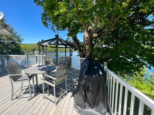 a table and chairs on a deck with a tree at Breathtaking Lake View With Spa Chalet 360 in Chertsey