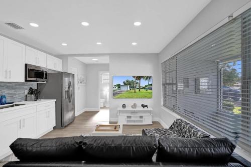a living room with a black couch and a kitchen at The Front Wave Luxury Home in Fort Lauderdale