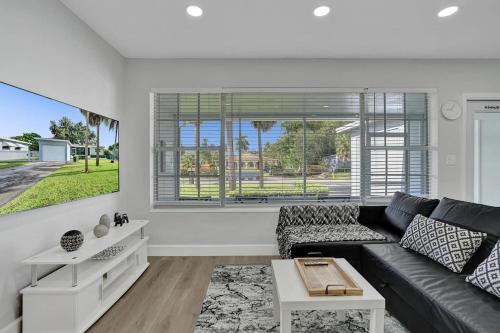 a living room with a black couch and a window at The Front Wave Luxury Home in Fort Lauderdale