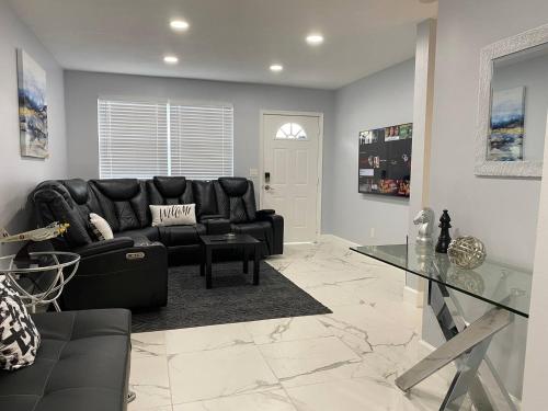 a living room with a black leather couch and a glass table at Mazor Luxury Three Bedrooms Vacation Home in Fort Lauderdale