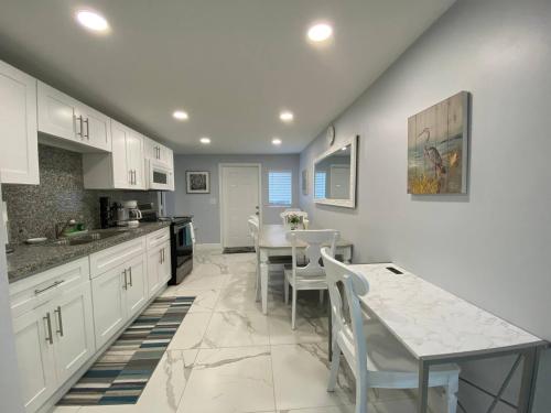 a kitchen with white cabinets and a table and chairs at Mazor Luxury Three Bedrooms Vacation Home in Fort Lauderdale